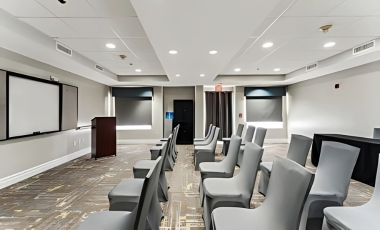 A conference room featuring chairs arranged around a projector screen, designed for business meetings at One Bedroom Suites Fort Lauderdale.