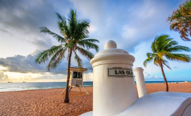 Lifeguard tower on a beach surrounded by palm trees, highlighting the coastal atmosphere near Fort Lauderdale's attractions.
