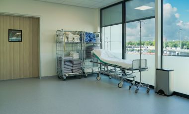 A hospital room featuring a bed, medical equipment, and a window, suitable for traveling nurses near Fort Lauderdale medical facilities.