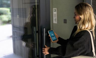 A woman holding a smartphone, gazing at a door, representing digital key access at a hotel near Fort Lauderdale Cruise Port.