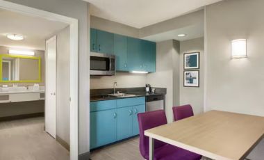 A small kitchen and dining area in a hotel room, featuring modern appliances and a cozy dining table.
