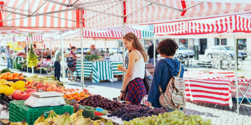 A lively outdoor market scene in Fort Lauderdale, featuring people shopping for fresh produce and local goods.