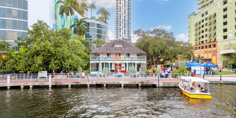 A boat is docked in front of Stranahan House Museum, overlooking the water in Fort Lauderdale.