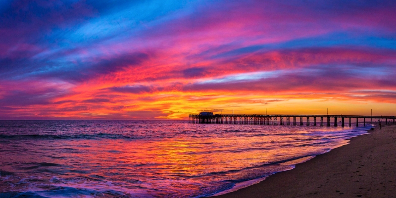 The sun sets in brilliant colors over the ocean, illuminating the Dania Beach Pier in Fort Lauderdale.