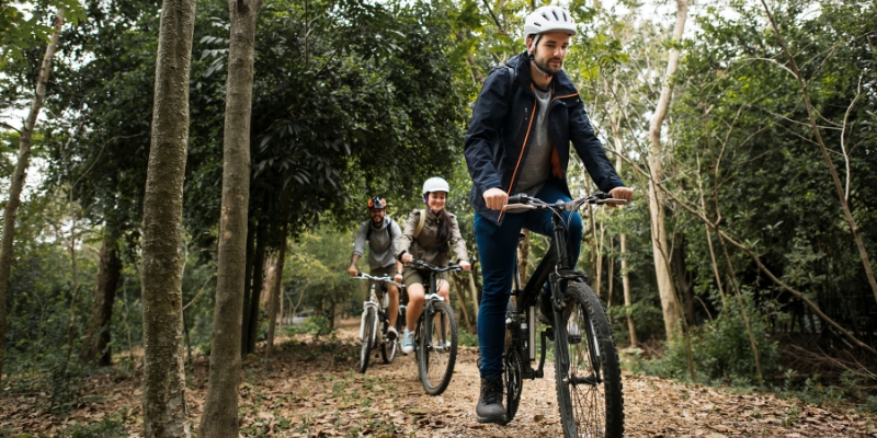 Three cyclists navigate a forested trail in Hugh Taylor Birch State Park, highlighting family-friendly activities in Fort Lauderdale.