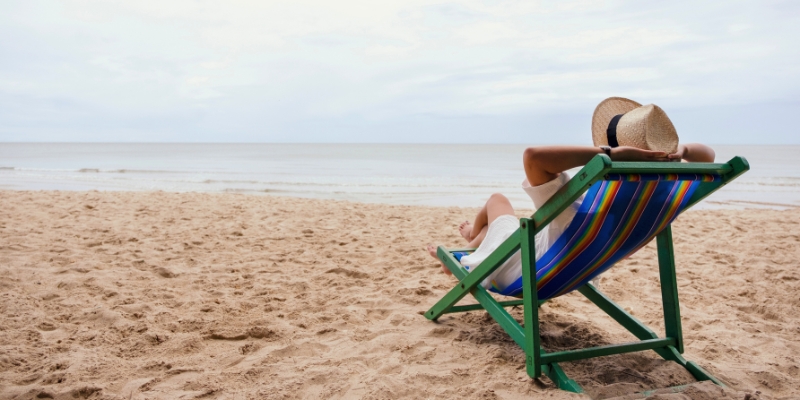 A person enjoys a sunny day in a beach chair on the sand at Fort Lauderdale Beach, embodying relaxation by the sea.