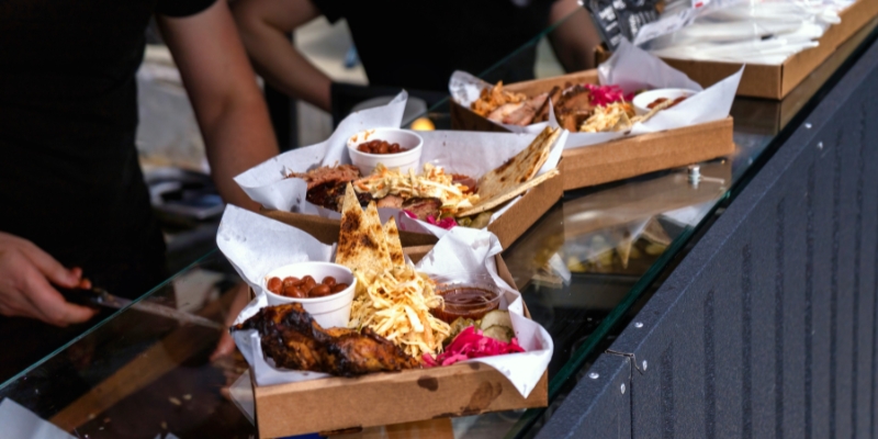 A man slices food in a box on a table, showcasing culinary activities at the Fort Lauderdale Food & Wine Festival.