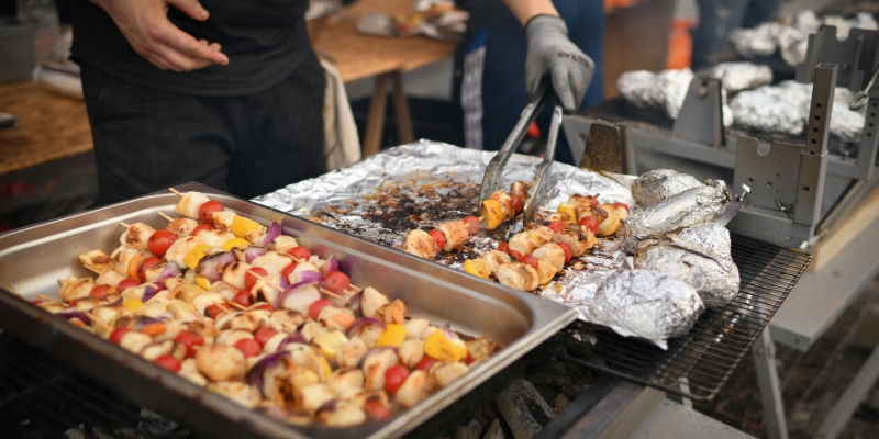 A person preparing food on a grill, set against the backdrop of a sunny spring day in Fort Lauderdale.