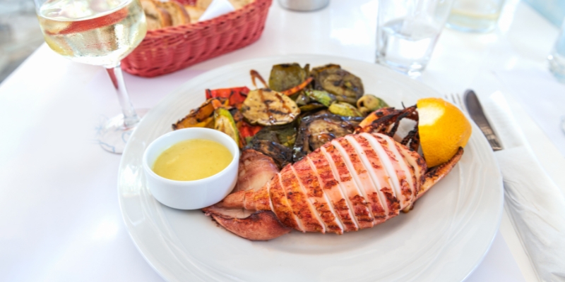A beautifully arranged plate of grilled lobster and vibrant vegetables, showcasing a summer culinary delight in Fort Lauderdale.