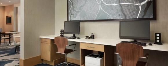 A well-appointed hotel room with a desk and two computers, ideal for business use near Dania Pointe.