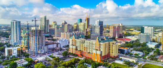 A skyline of tall buildings surrounded by trees, highlighting Florida Package at Hampton Inn & Suites Fort Lauderdale.